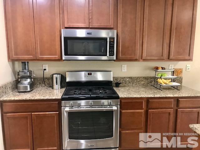 8950 Convair Way Reno, NV 89506 - Photo 6 of 26 a kitchen with granite countertop stainless steel appliances a stove a microwave and sink