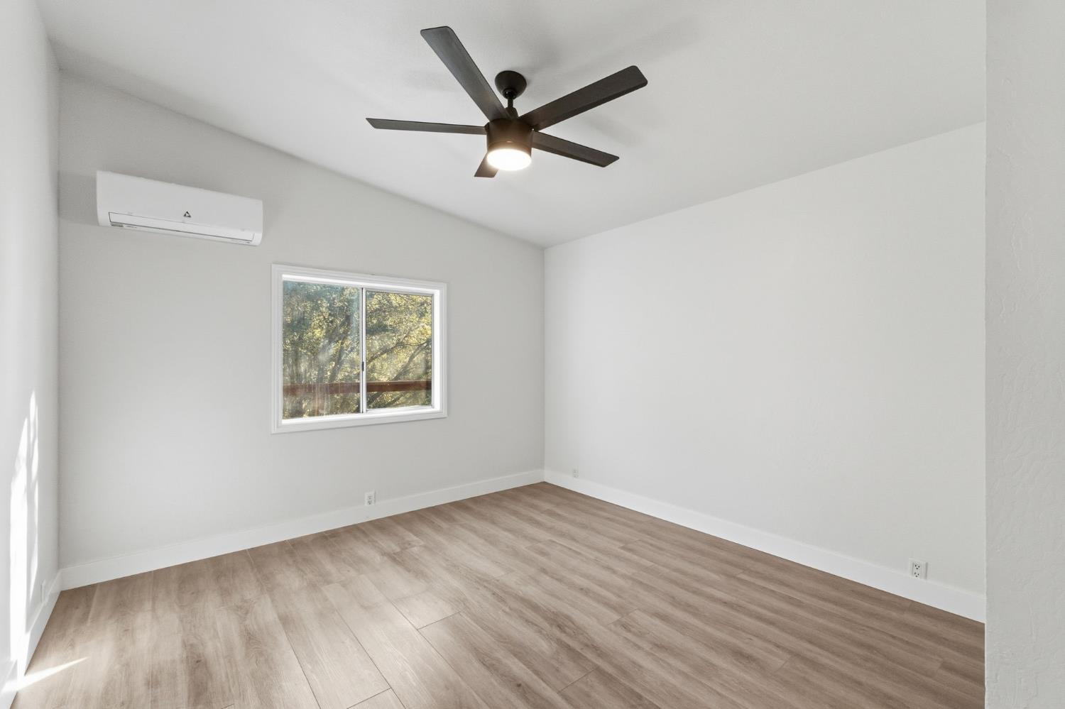 40089 John West Road Oakhurst, CA 93644 - Photo 27 of 59 an empty room with wooden floor ceiling fan and windows