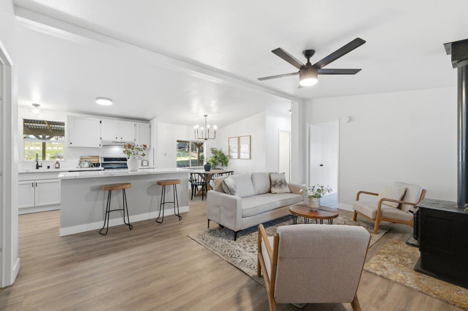 40089 John West Road Oakhurst, CA 93644 - Photo 9 of 59 a living room with couches a kitchen with kitchen island stainless steel appliances wooden floor and a refrigerator