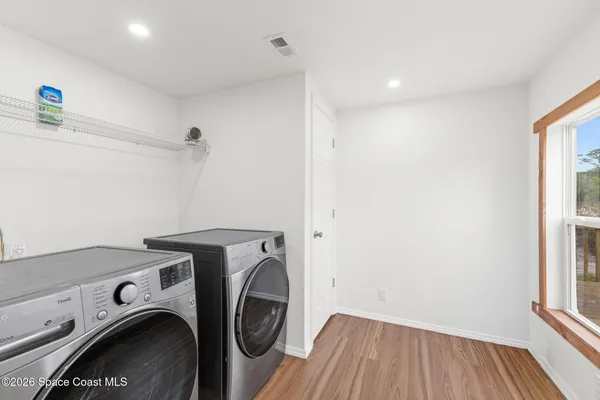 a view of an empty room with a window and wooden floor