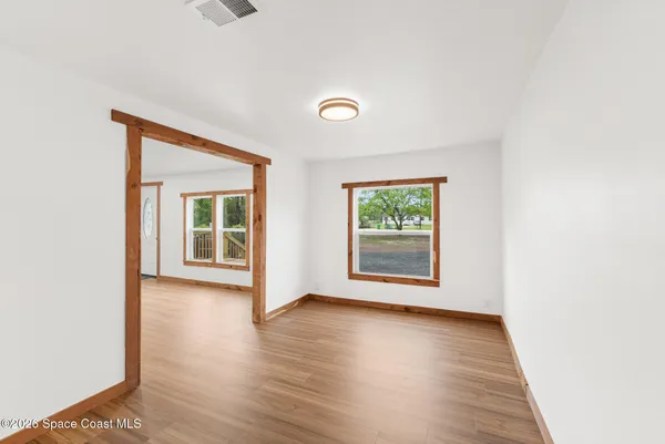 a view of a room with wooden floor and a kitchen