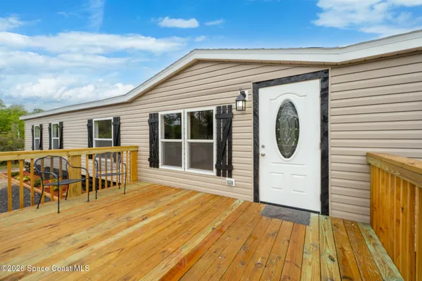 a view of a house with wooden deck and furniture