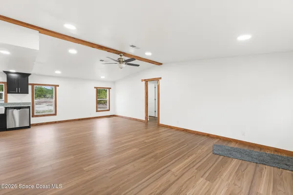 a view of an empty room with wooden floor and a window