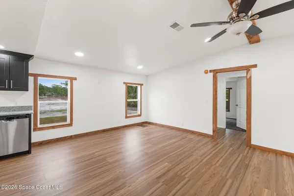 a view of an empty room with wooden floor and a window