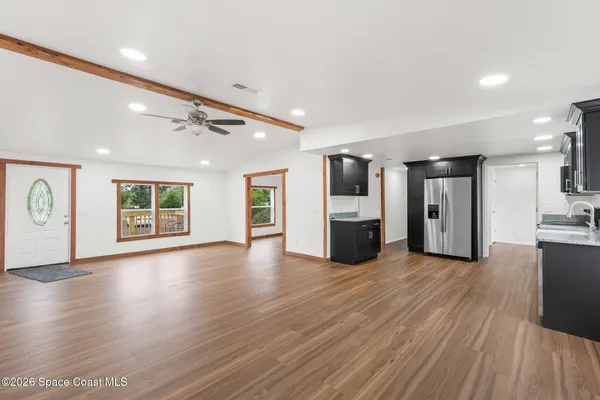 a view of an empty room with window and wooden floor