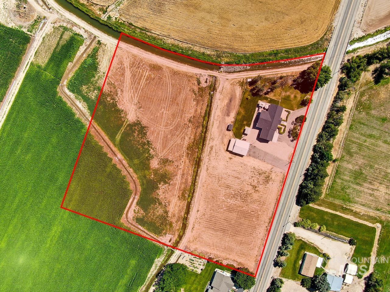 4950 West Columbia Road Nampa, ID 83687 - Photo 46 of 50 Expansive property featuring a residence with a dark roof, a detached structure, paved driveway, and surrounding agricultural fields
