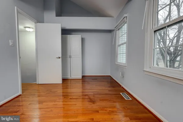 an empty room with wooden floor and windows