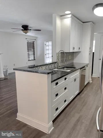 a kitchen with granite countertop a sink cabinets and wooden floor