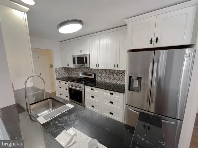 a kitchen with granite countertop a refrigerator stove and sink