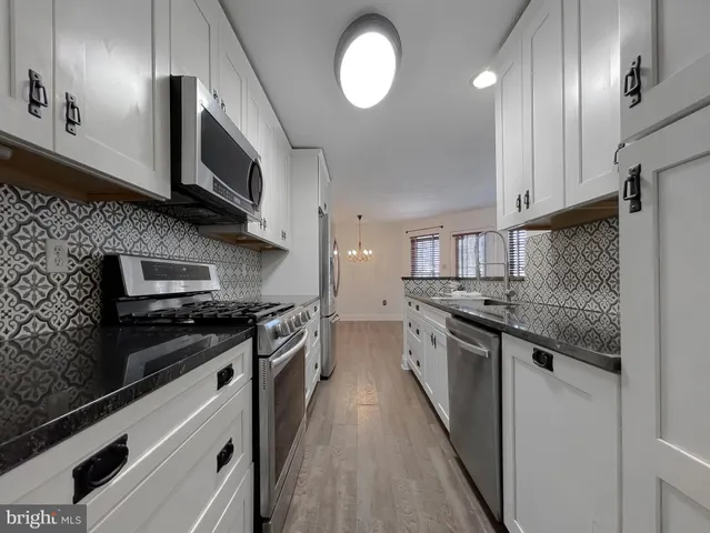 a kitchen with stainless steel appliances granite countertop a stove top oven a sink and a microwave