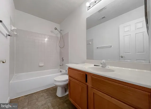 a bathroom with a granite countertop sink a toilet and a mirror
