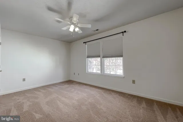 a view of an empty room with chandelier fan