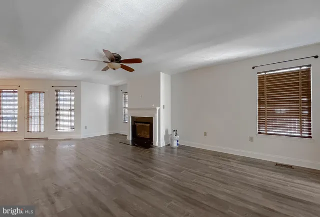 a view of an empty room with a fireplace and wooden floor