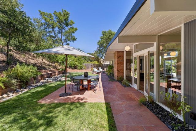 a view of a patio with chairs and table under an umbrella
