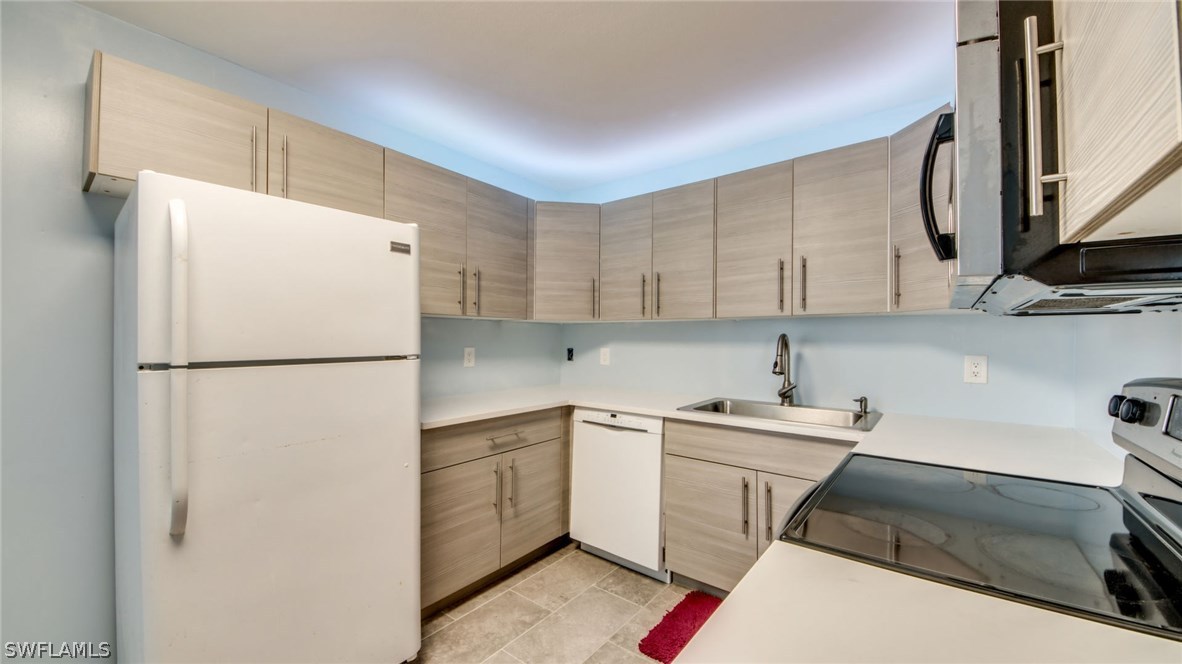 101 Oregon Road West Lehigh Acres, FL 33936 - Photo 10 of 24 a kitchen with a sink a refrigerator and cabinets