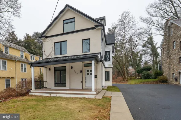 a view of a white house with large windows and a small yard