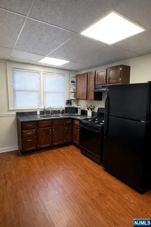 a kitchen with stainless steel appliances granite countertop a refrigerator a sink a stove a microwave and wooden floors