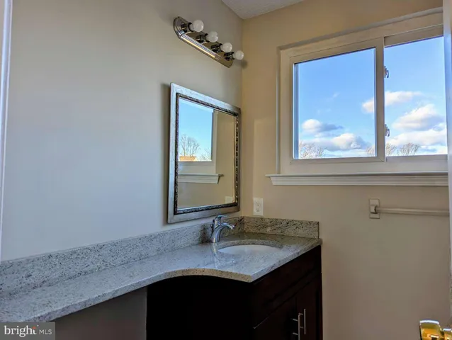 a bathroom with a granite countertop sink and a mirror