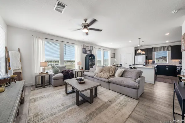 a living room with furniture kitchen view and a large window