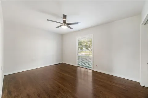 an empty room with wooden floor fan and windows