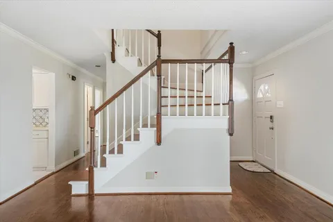 a view of staircase with lots of frames on wall and wooden floor