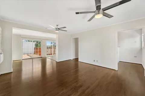 a view of an empty room with wooden floor and a ceiling fan
