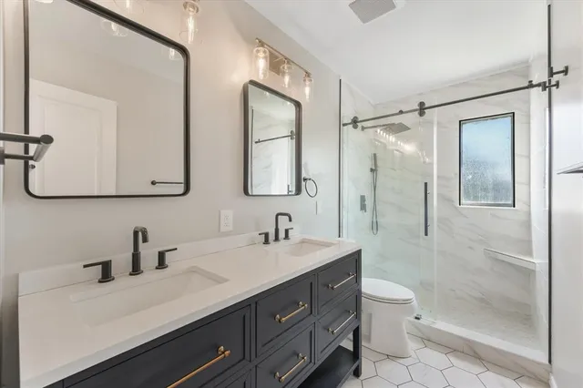 a bathroom with a double vanity sink toilet mirror and shower