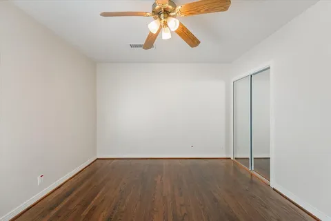 an empty room with wooden floor and chandelier fan