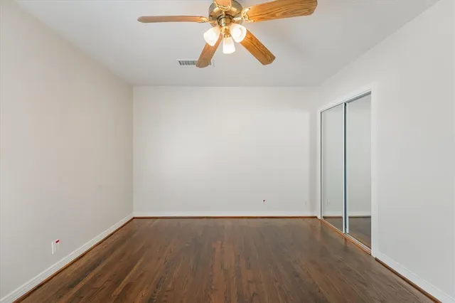 an empty room with wooden floor and chandelier fan