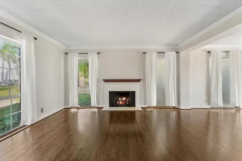 a view of wooden floor fire place and windows in a room