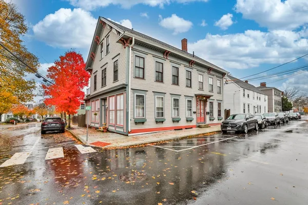 a front view of a building with lot of cars and trees around