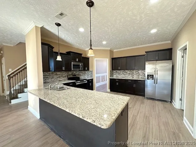 a large kitchen with kitchen island a large counter top and stainless steel appliances