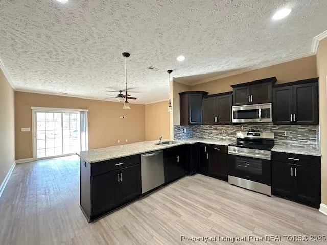 a large kitchen with stainless steel appliances granite countertop a stove a sink dishwasher a microwave oven and a refrigerator with wooden floor