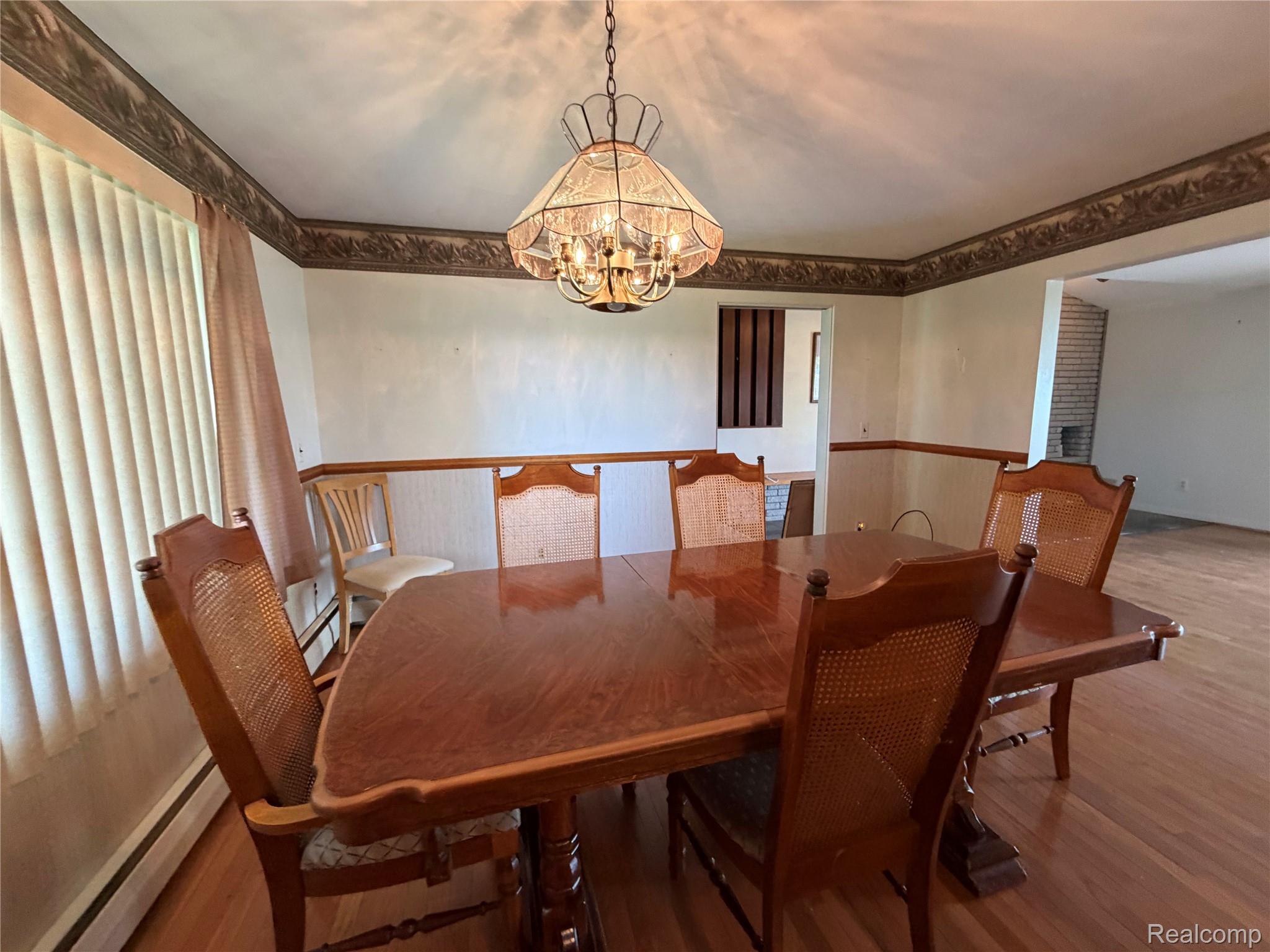 8886 East Burnside Road Brown City, MI 48416 - Photo 11 of 22 Dining area featuring wood-finish flooring, wainscoting, and a decorative ceiling light fixture