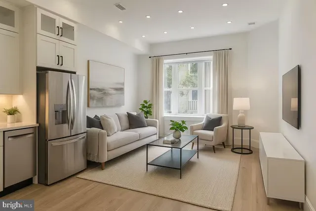 a living room with furniture a large window and a refrigerator