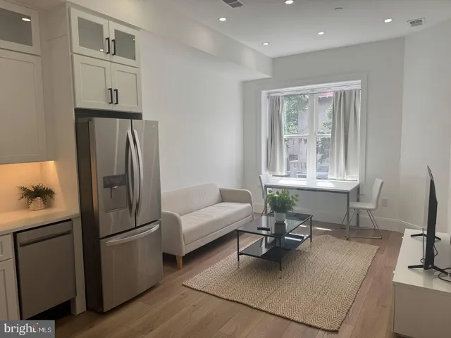 a living room with furniture a dining table and a refrigerator