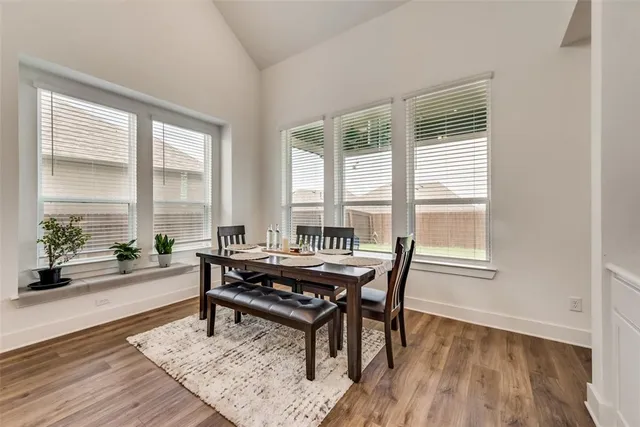 a dining room with wooden floor and windows