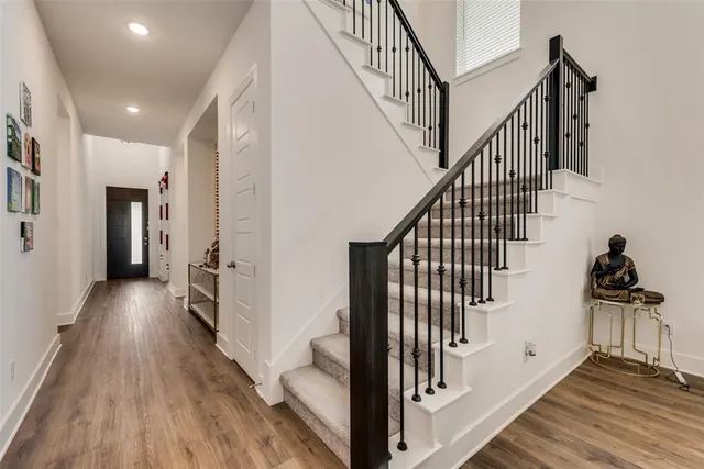 a view of a hallway with wooden floor and staircase