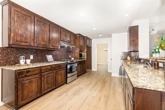a kitchen with granite countertop wooden cabinets a sink and dishwasher