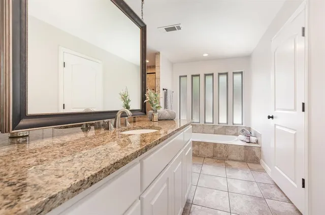 a bathroom with a granite countertop sink and a bathtub