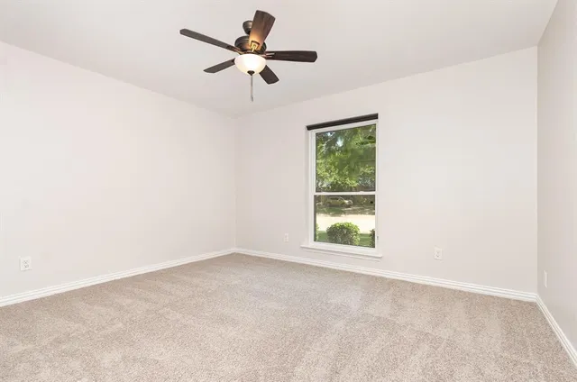 an empty room with a window and a fan