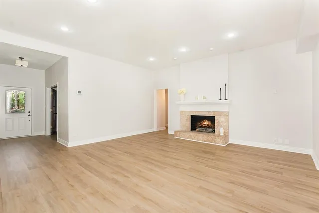 a view of an empty room with wooden floor fireplace and a window
