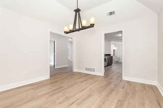 a view of a hallway with wooden floor and a chandelier