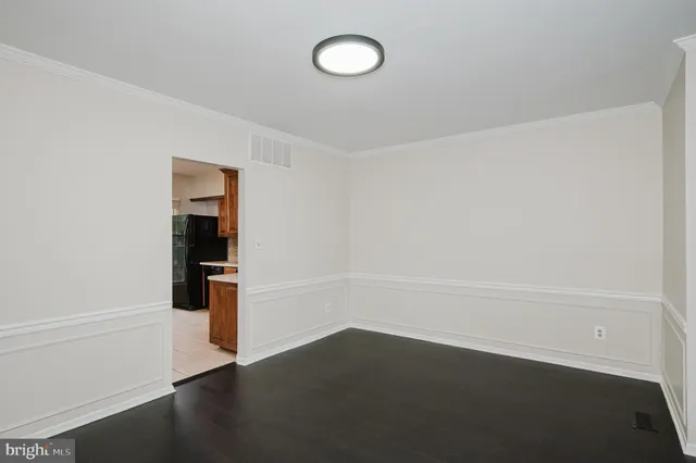 a view of an empty room with wooden floor and cabinet