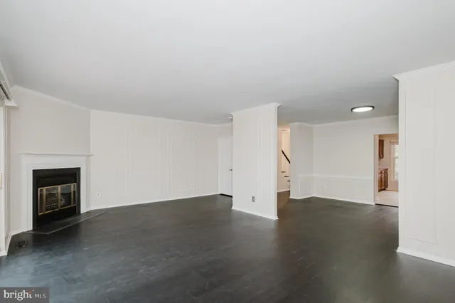 a view of an empty room with wooden floor fireplace and a window