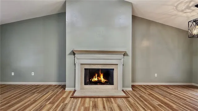 a view of an empty room with wooden floor fireplace and a window