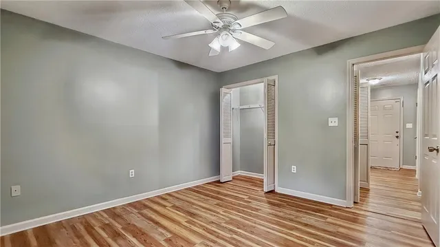 a view of a room with a chandelier fan and wooden floor