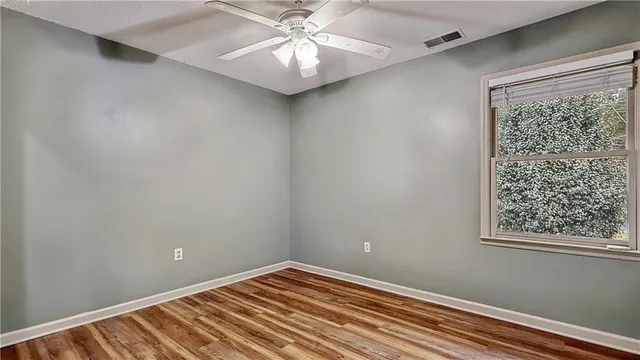 en empty room with wooden floor and windows