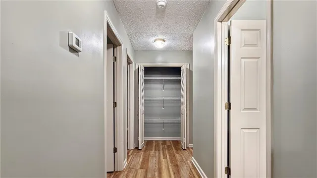 a view of a hallway with wooden floor and closet area