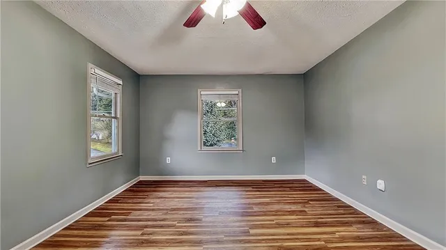 a view of an empty room with wooden floor and window